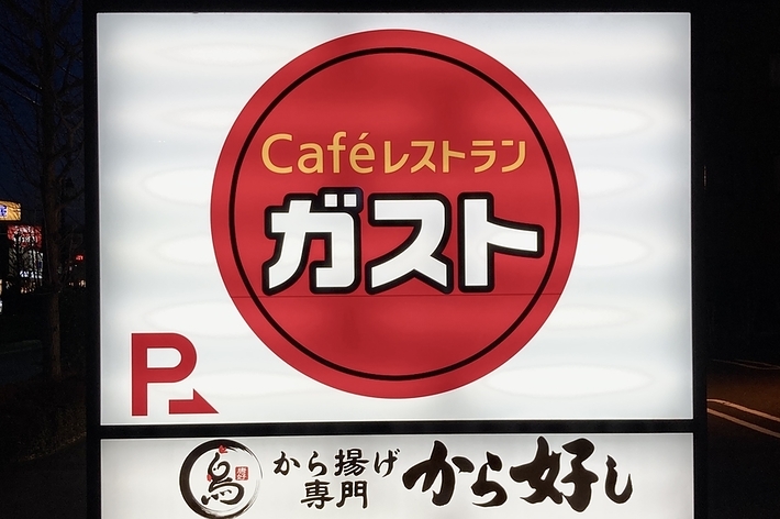 夜の「Caféレストラン ガスト」の看板。下部には「から揚げ専門 から好し 店内飲食・お弁当・お持ち帰り」と書かれている。