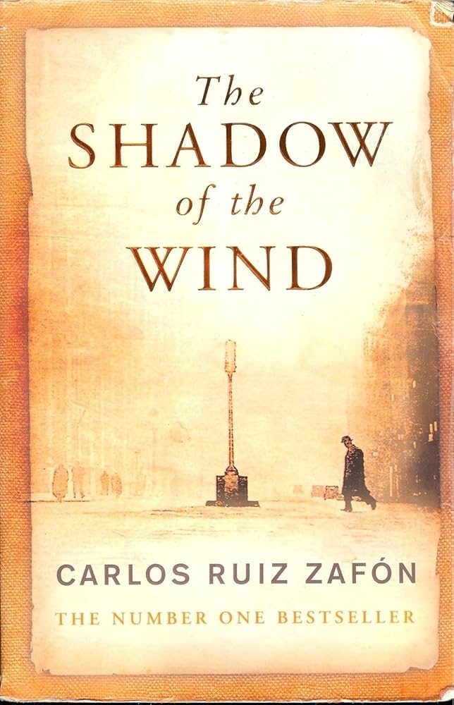 Cover of Carlos Ruiz Zafón's bestseller "The Shadow of the Wind," featuring a lone figure walking in a misty street with a lamppost in the center