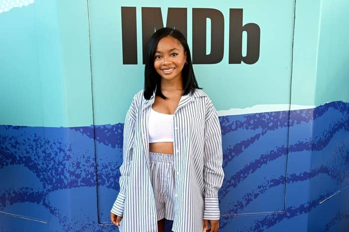Skai Jackson posing in a striped shirt and shorts, in front of an IMDb backdrop