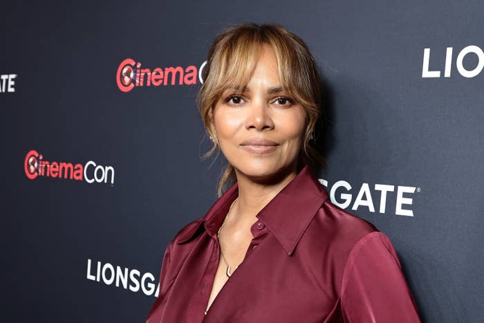 Halle Berry poses on the Lionsgate event red carpet, wearing a sleek button-up shirt with bangs framing her face