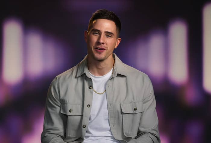 A man in a T-shirt and light jacket speaks during an interview