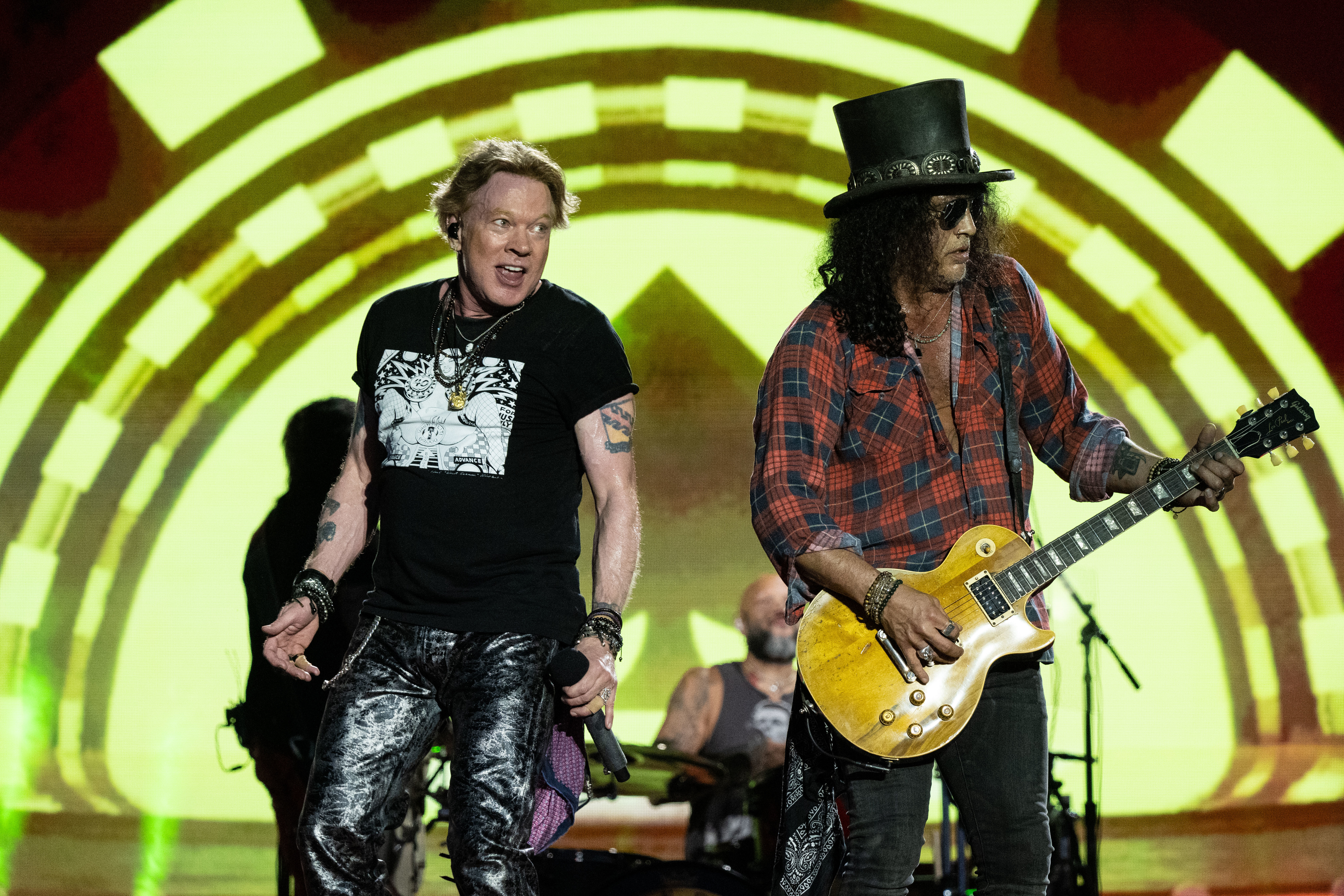 Axl Rose and Slash performing on stage, with Axl singing and Slash playing guitar