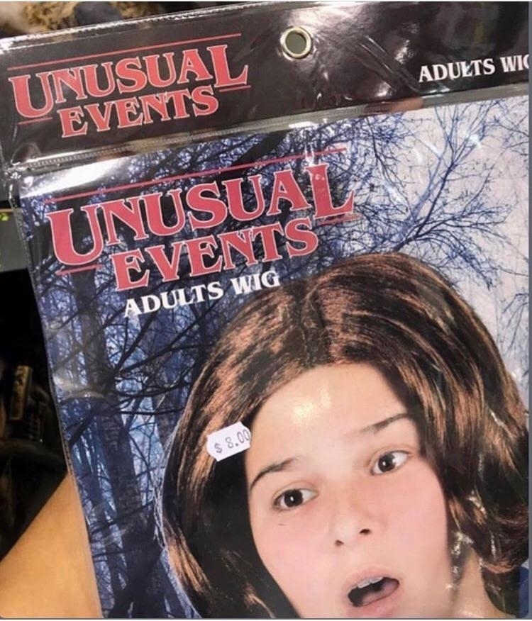 A package of an "Unusual Events Adults Wig" featuring a person with a shocked expression and medium-length brown hair. Price tag shows $8.00