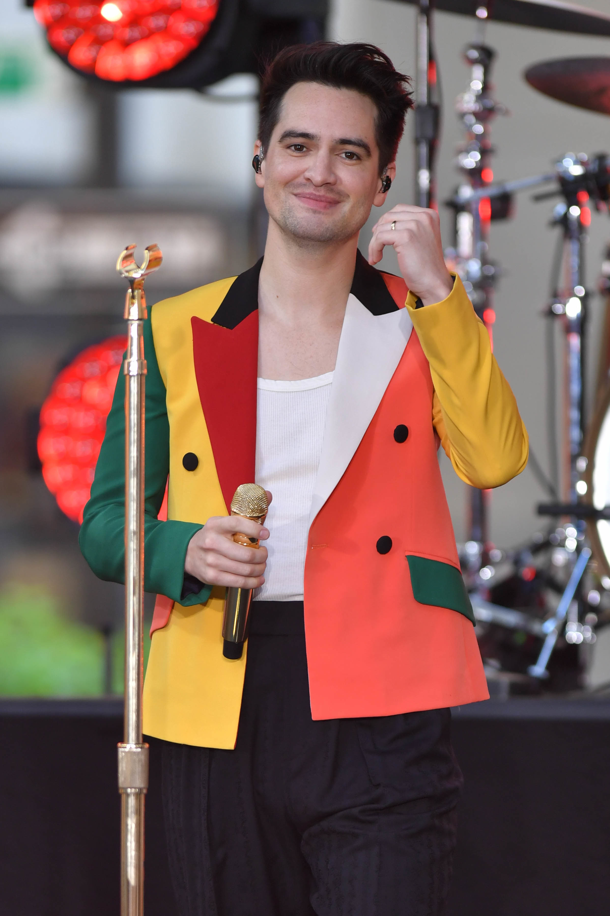 Brendon Urie performs on stage wearing a colorful, multi-paneled jacket