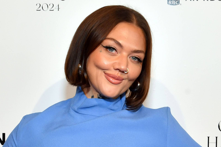 女性が立っている。黒地に赤い花柄のドレスを着ている。背景には「LIBERTY & JUSTICE FOR ALL AWARD」の文字。