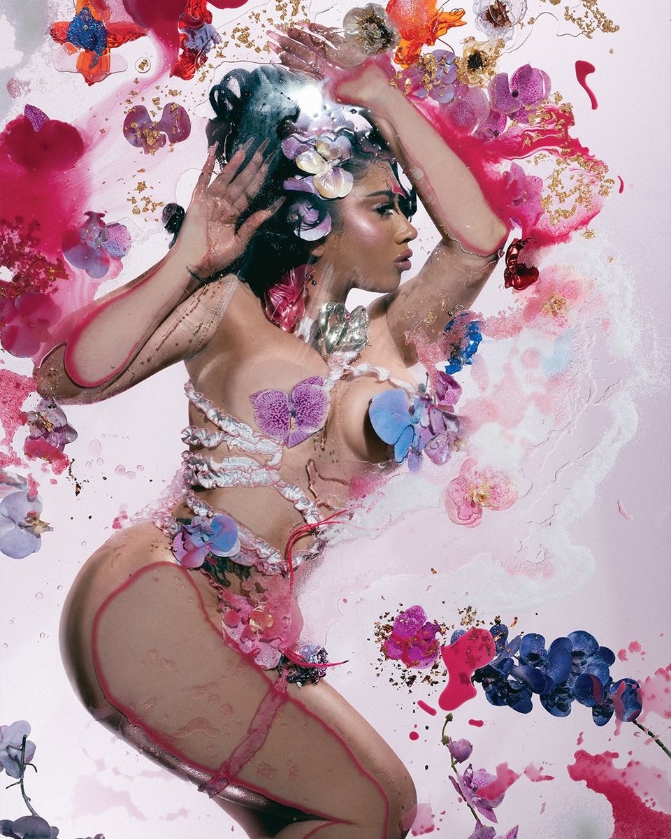 Kali Uchis poses artistically with flowers adorning her body in a floral-themed photoshoot