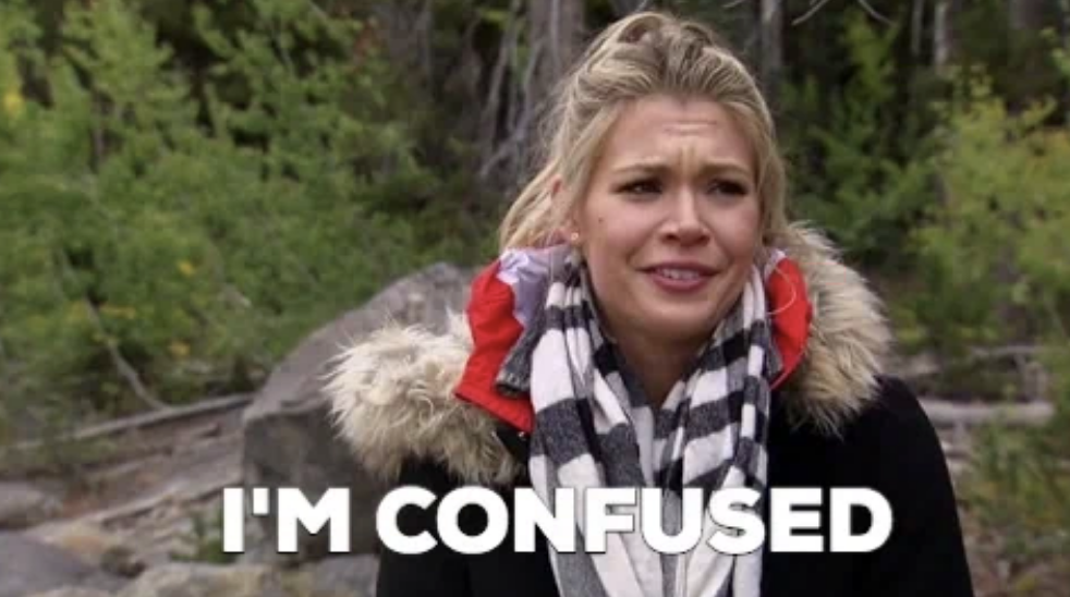 Woman outdoors looks baffled with text overlay: &quot;I'M CONFUSED&quot;. She wears a checkered scarf and jacket with fur trim