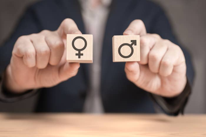 Person holding two wooden blocks, one with a female gender symbol and the other with a male gender symbol