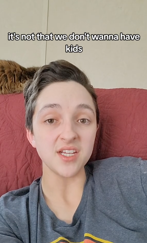 Person in a casual shirt discussing the topic of not wanting kids, with text reading "it's not that we don't wanna have kids" above