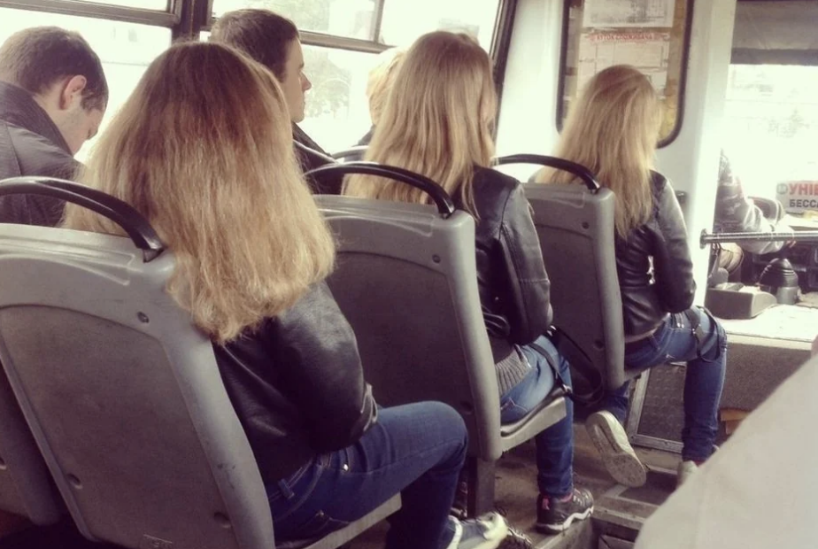 People sitting on a bus. Several individuals have similar hairstyles and jackets, all facing forward