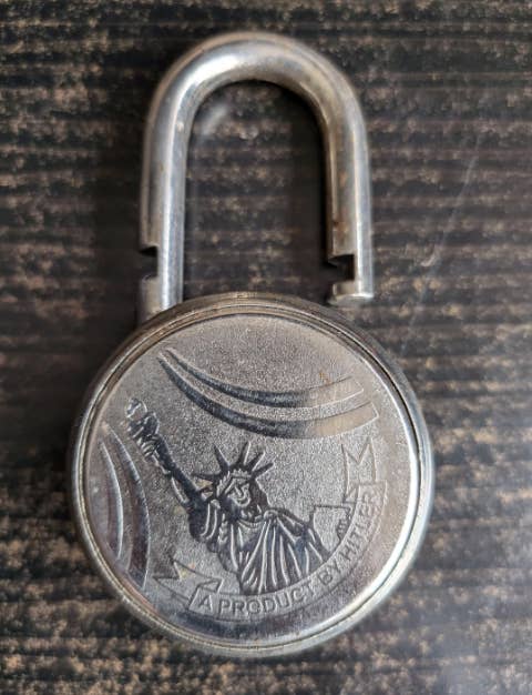 Old metal padlock with an engraving of the Statue of Liberty and the text "A Product Standard"