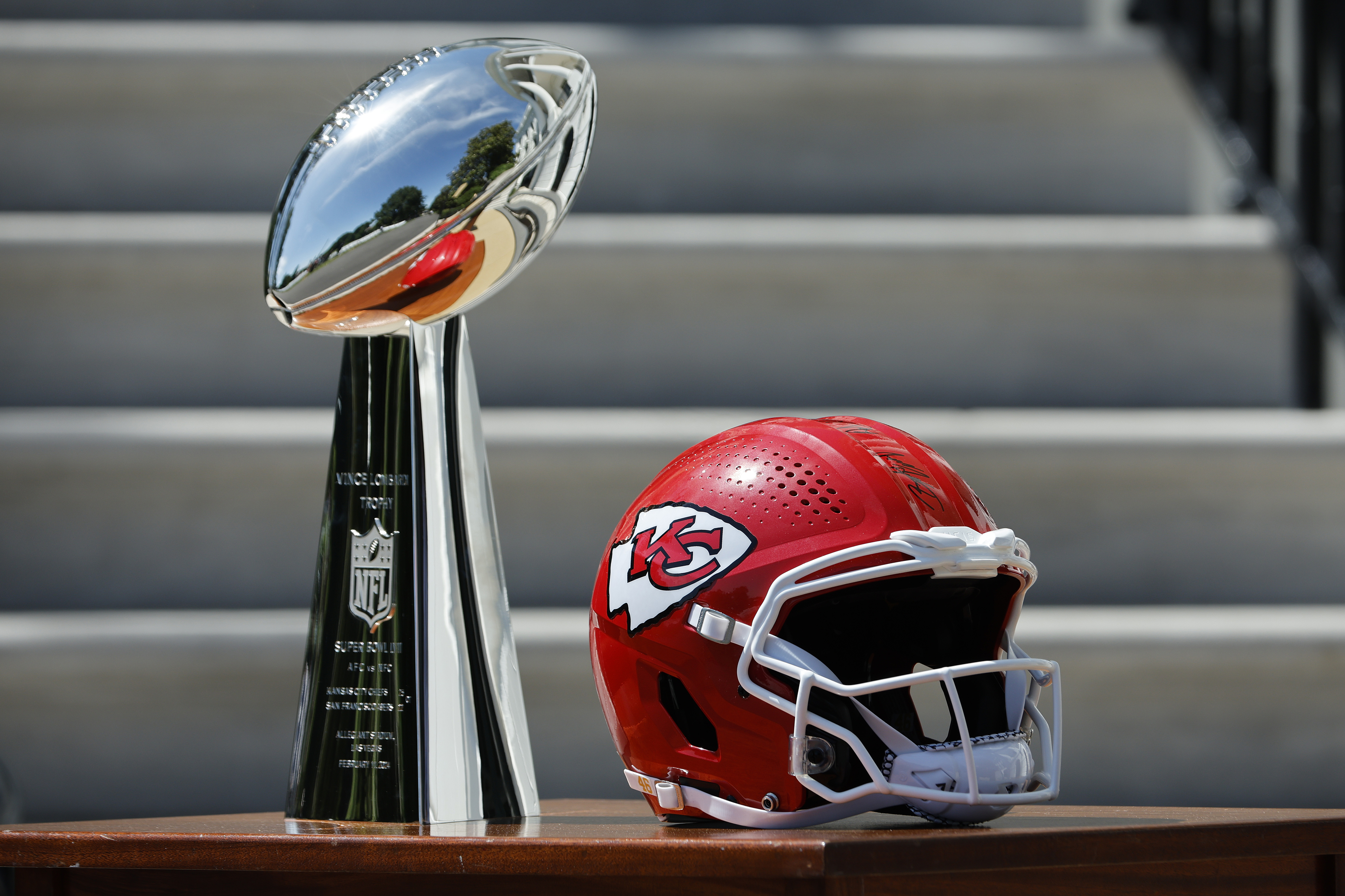 A Lombardi Trophy and a Kansas City Chiefs football helmet are displayed on a tabletop