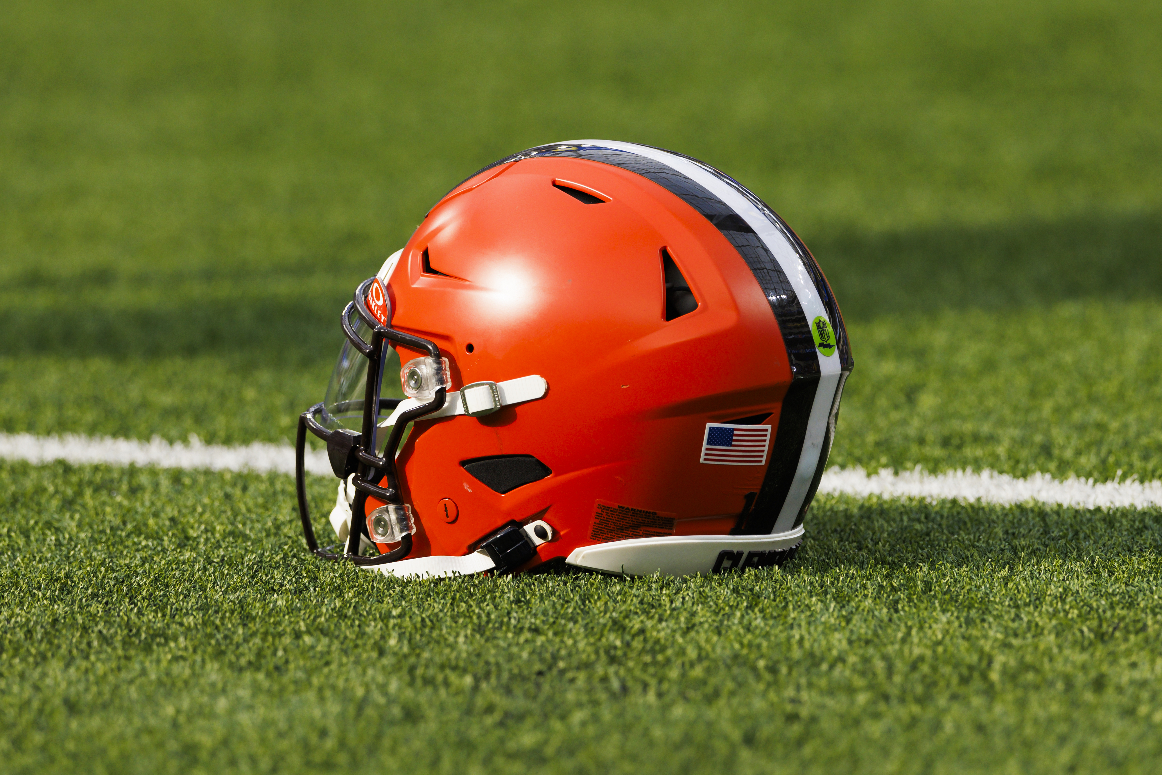 An orange football helmet sitting on a field