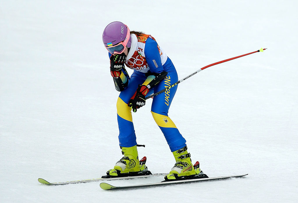 Olympic skier Olena Bilosiuk, in blue and yellow gear, stands on the snowy slope during a race