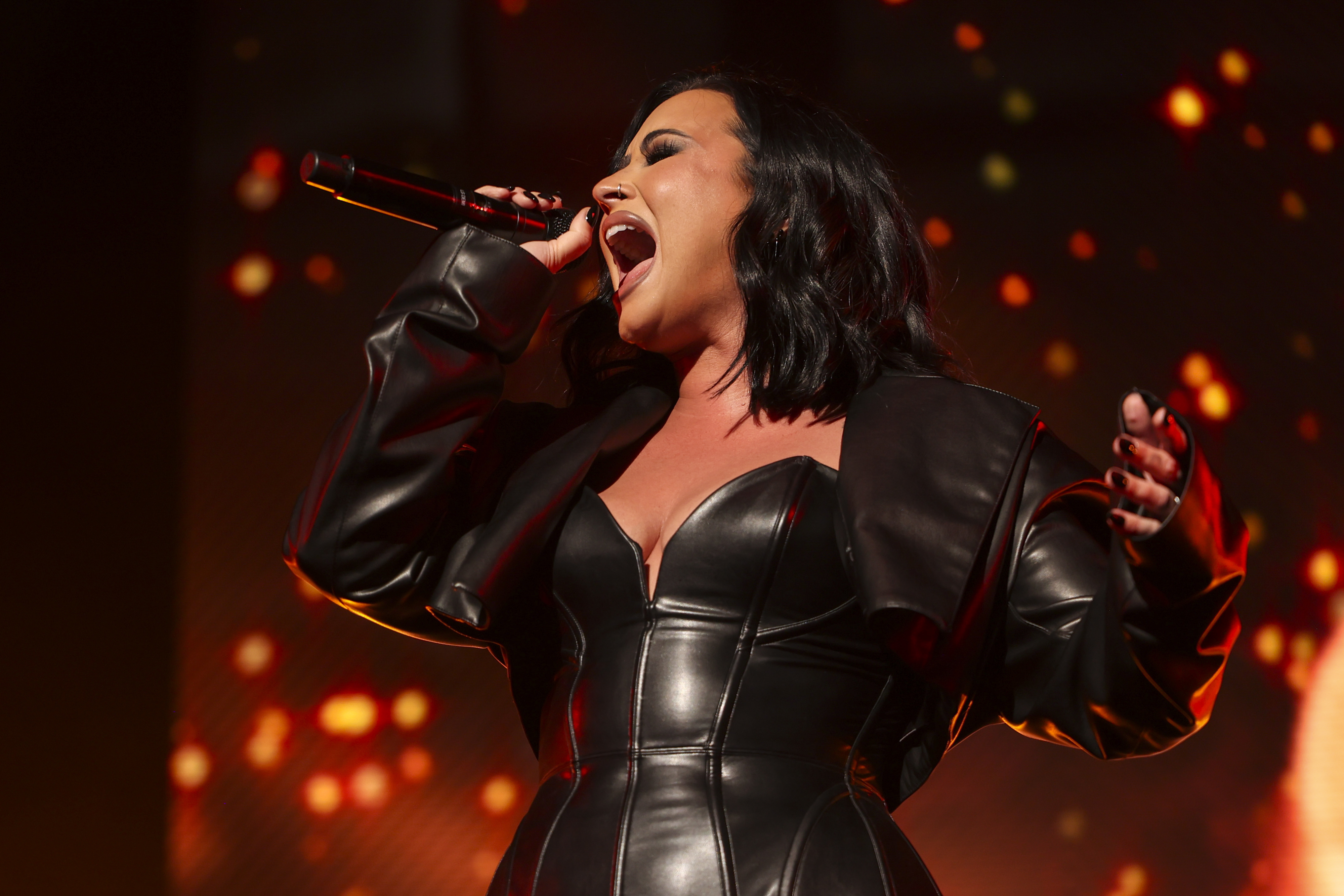 Demi Lovato performs passionately on stage, wearing a stylish leather outfit