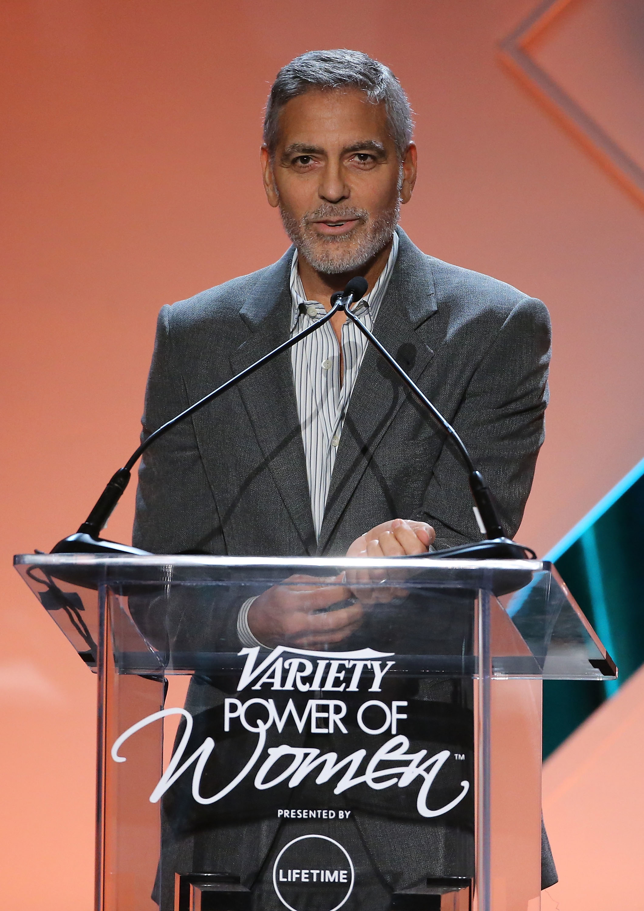 George Clooney speaking at a podium with a "Variety Power of Women" sign