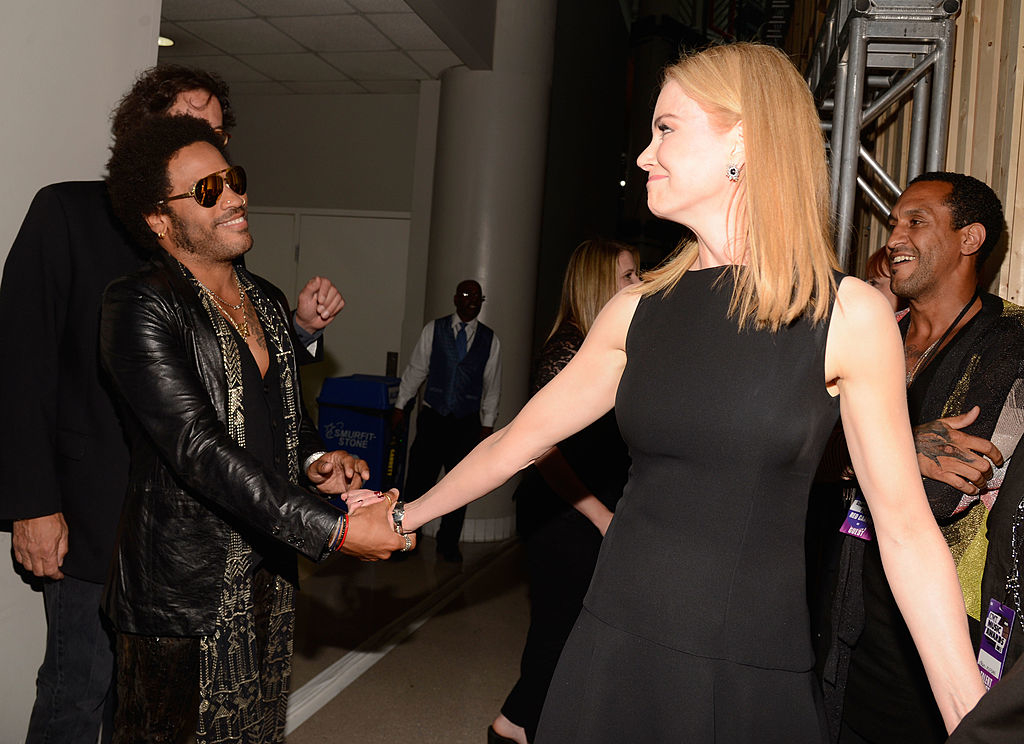 Lenny Kravitz shakes hands with Nicole Kidman, who is in a dark dress, backstage at an event