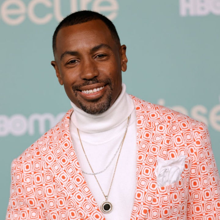 Man in patterned blazer over a white turtleneck, smiling at the camera