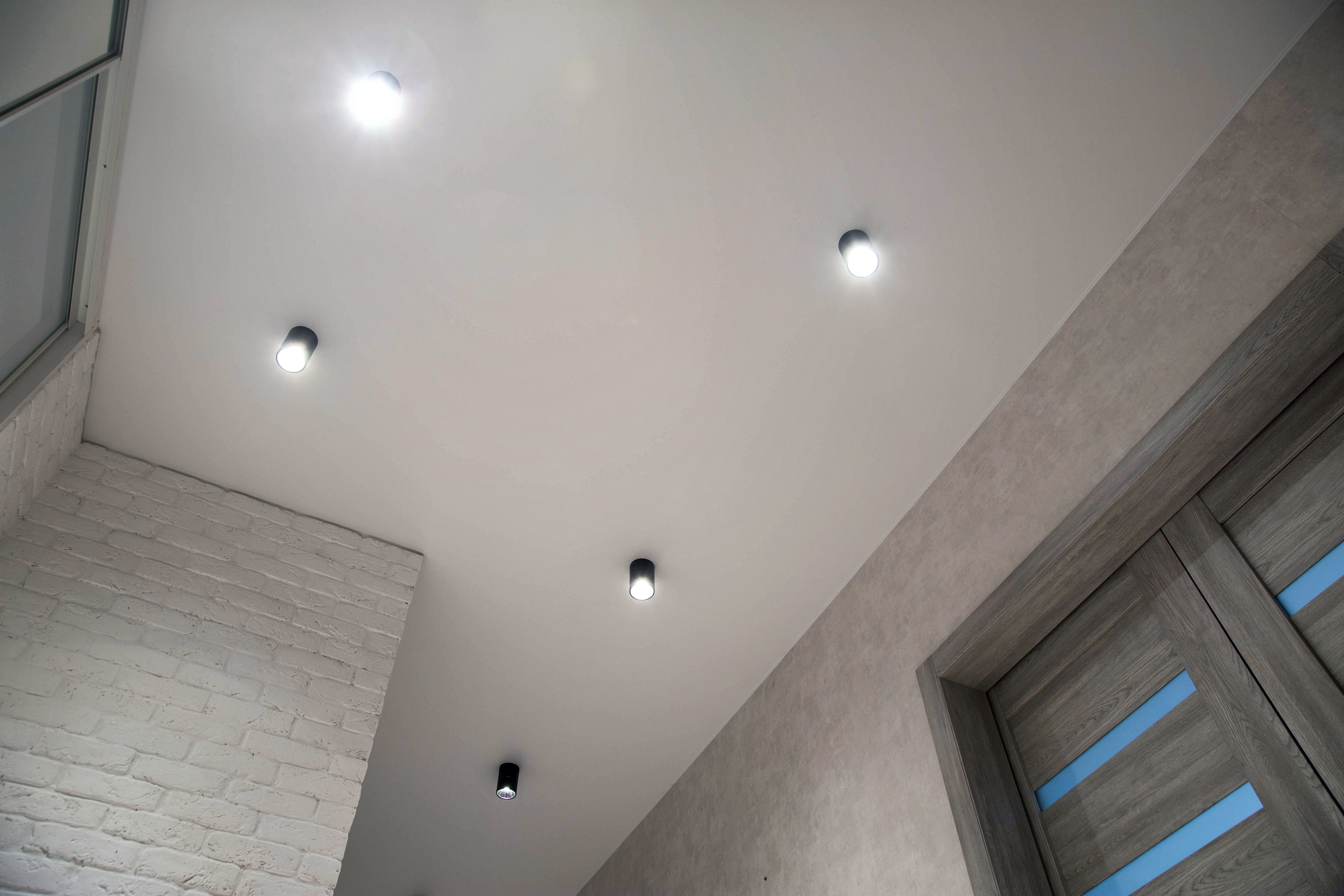 Ceiling with five recessed lights, view includes a white brick wall and a partially visible window with blinds