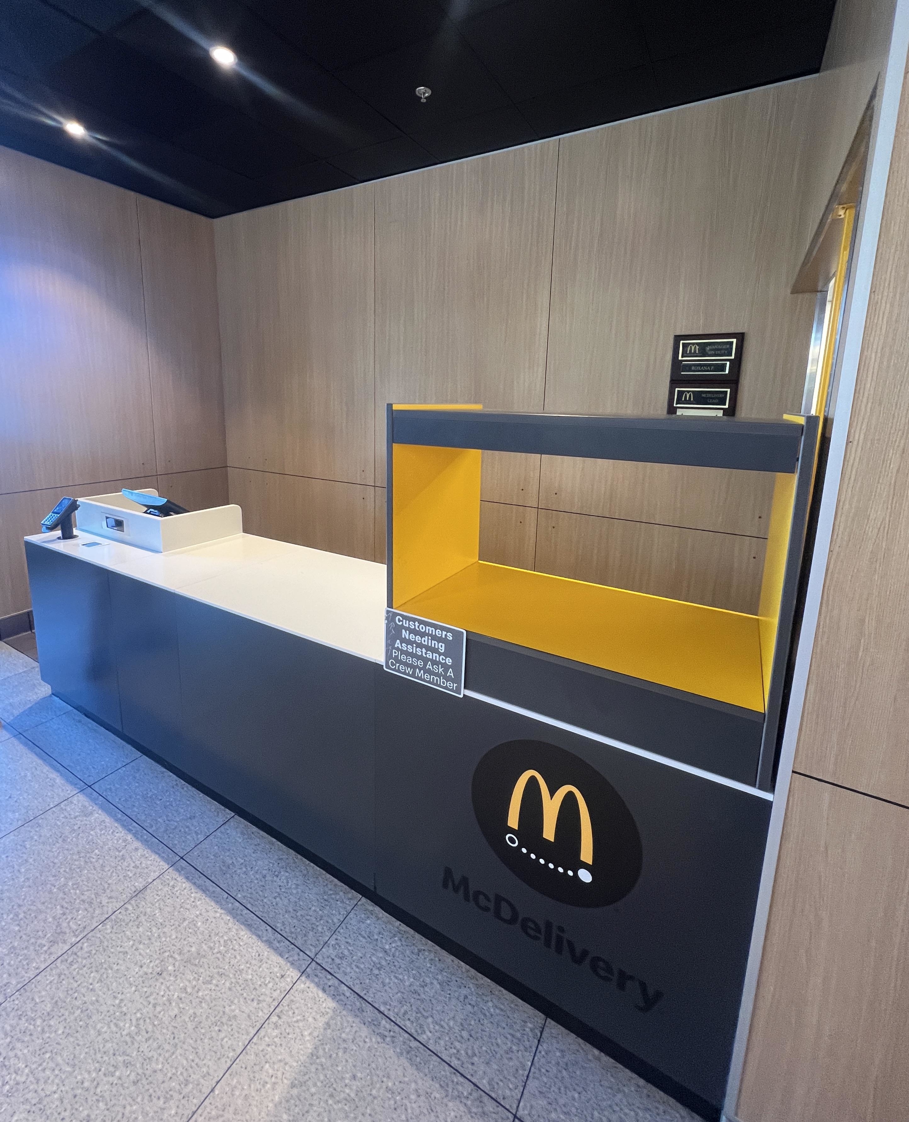 McDonald's McDelivery counter with an ordering kiosk. A sign displays "Customers waiting: after kiosk order, please wait."