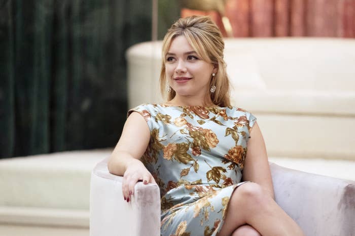 Florence Pugh sitting in an elegant chair, wearing a floral-patterned dress in a scene from "Don't Worry Darling"