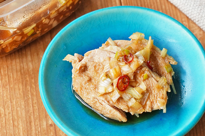 鮮やかな青い皿に盛り付けられた、ネギや唐辛子をトッピングした鶏肉の料理がテーブルに置かれています。