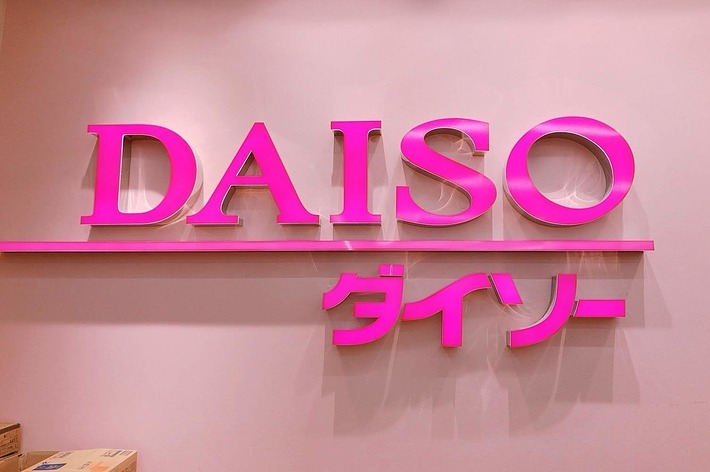 ピンクの背景に「DAISO」と「ダイソー」の文字が表示されている看板。
