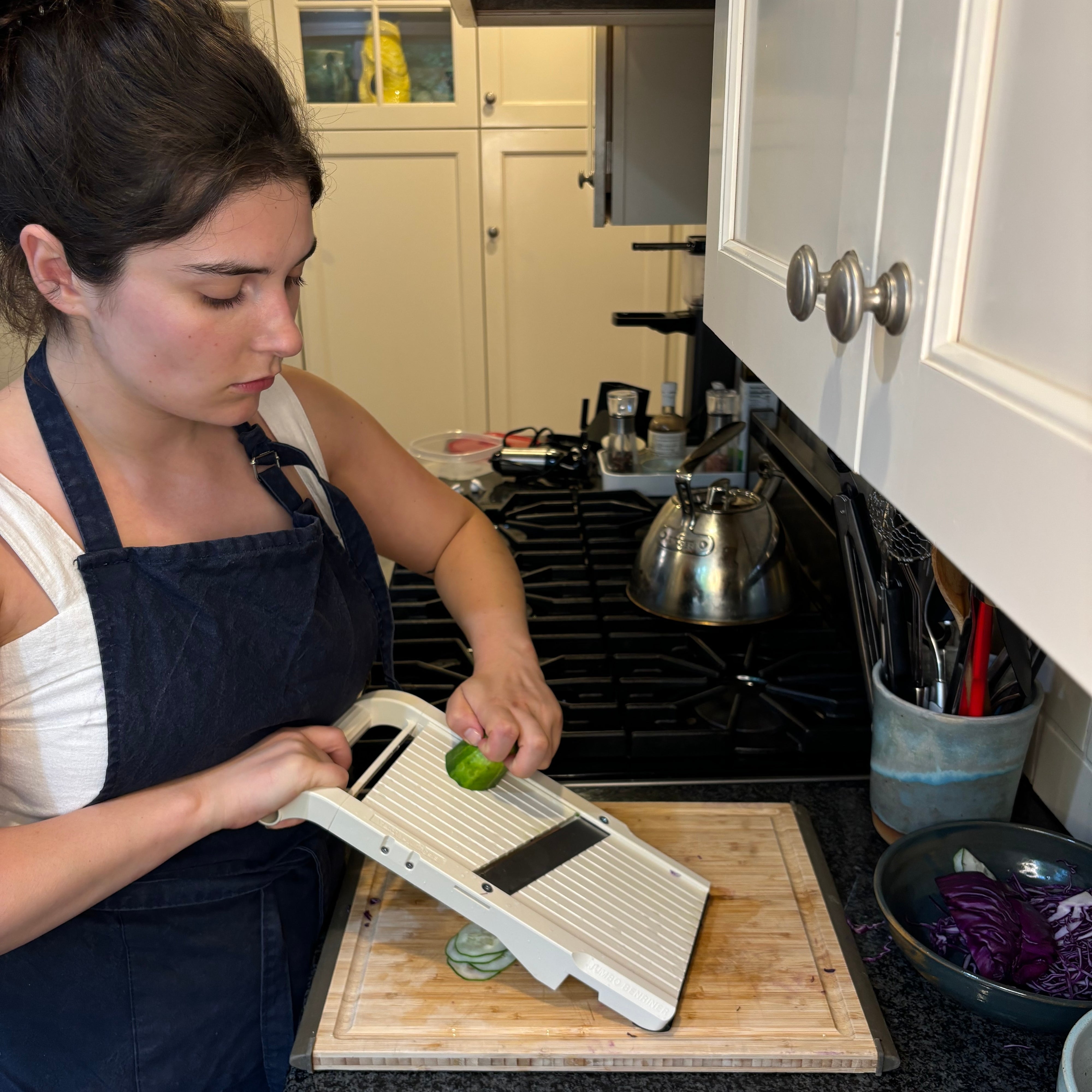 A person slices vegetables with a mandoline in a kitchen