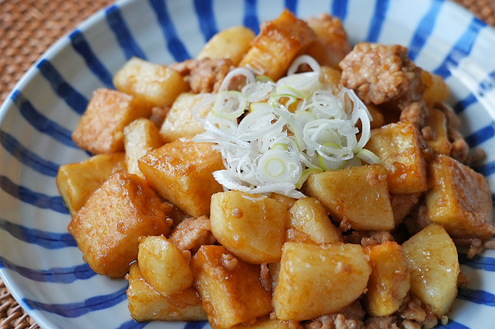 お皿に盛られたジャガイモの炒め物。上には薄く切ったネギが載せられている。