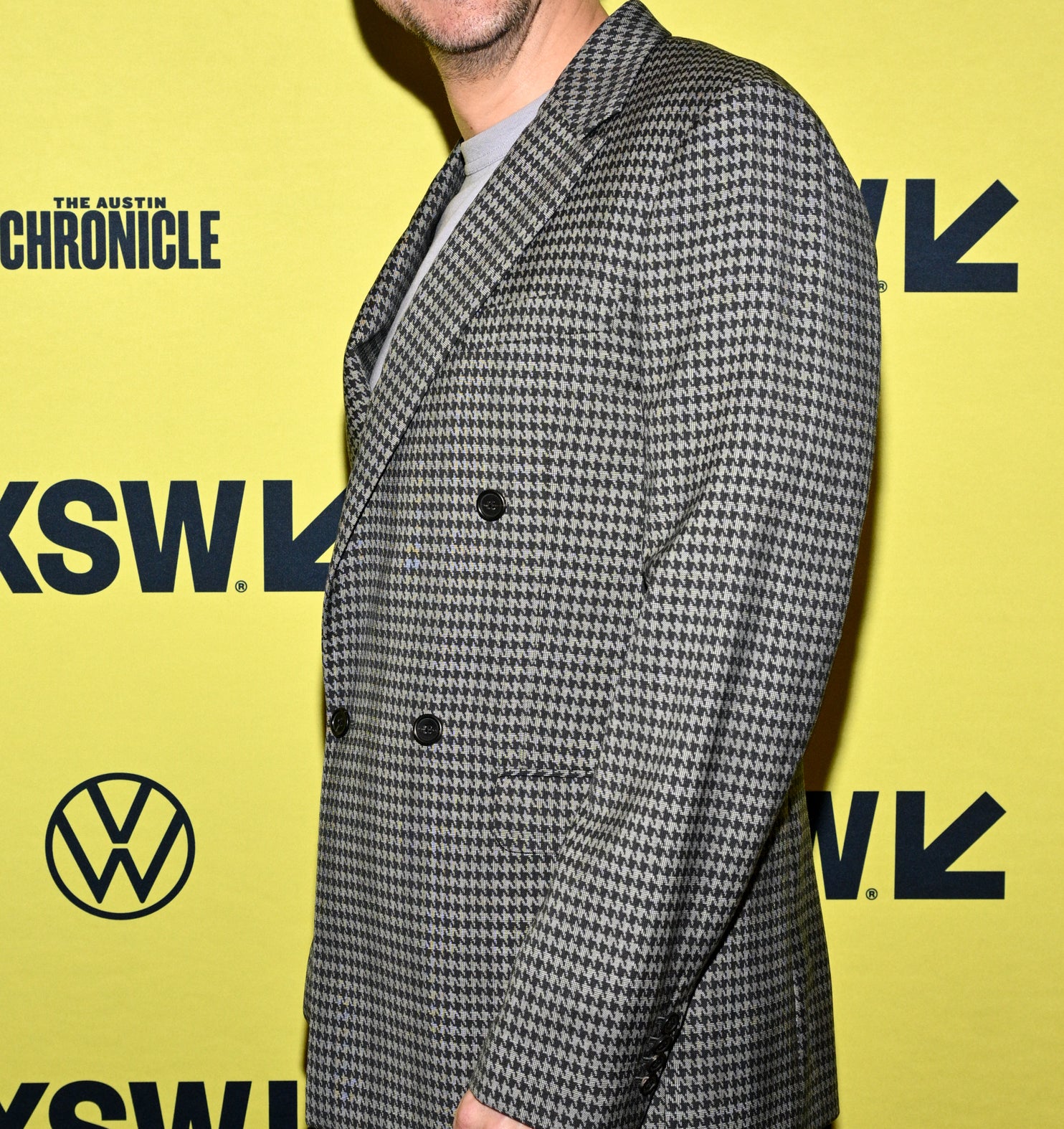 Dan Stevens smiling in a checkered suit, standing in front of a SXSW backdrop