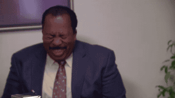 Stanley Hudson from The Office laughs heartily while sitting in what appears to be an office setting