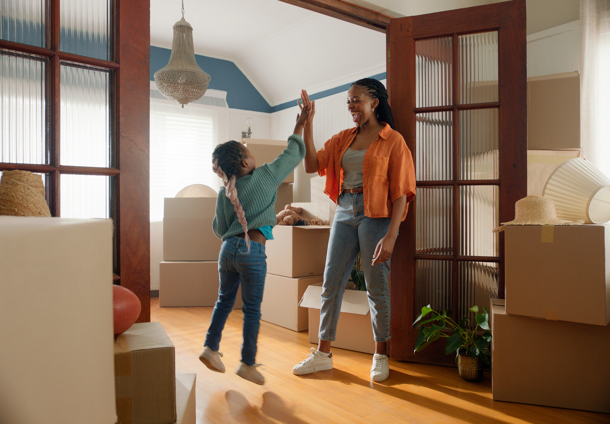 A mother and daughter high-fiving in a house full of boxes