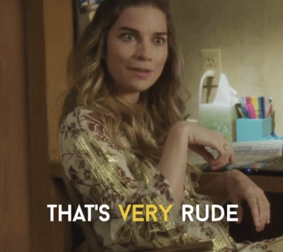 A woman with long wavy hair, wearing a patterned outfit, sits in a chair inside a home, looking surprised. The text overlay reads, &quot;THAT'S VERY RUDE.&quot;