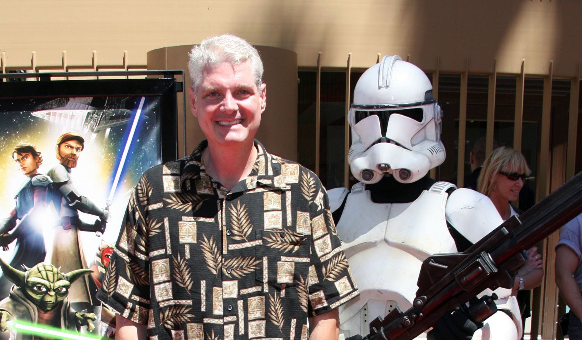Tom Kane in a patterned shirt stands next to a person dressed as a stormtrooper at a red carpet event for "Star Wars: The Clone Wars"