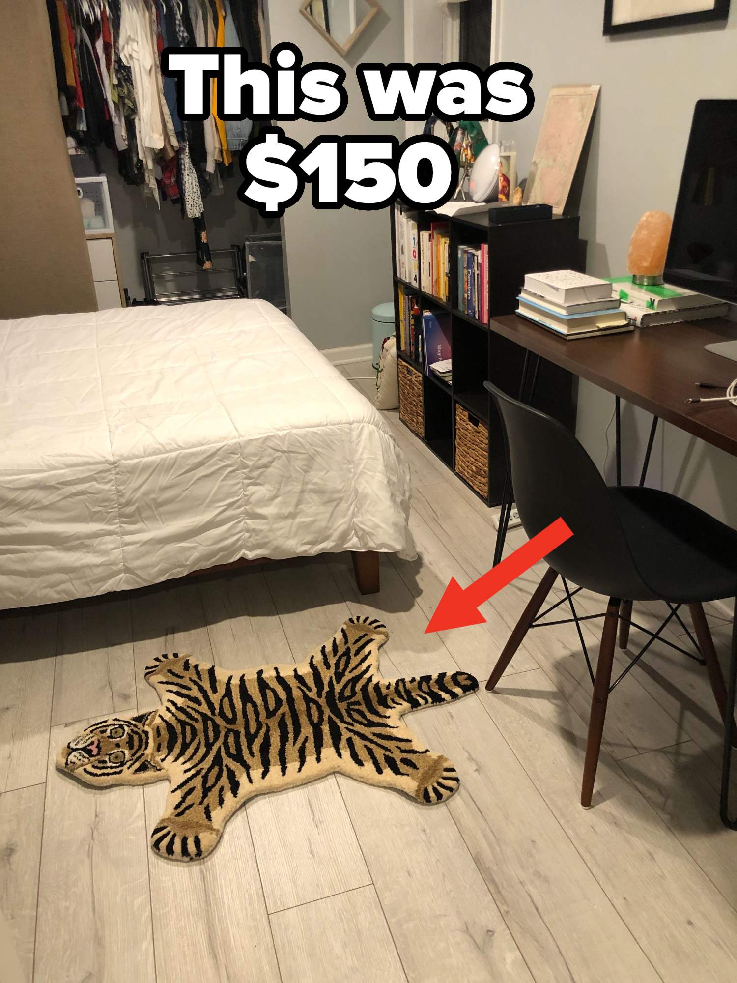 A bedroom scene featuring a bed, a tiger-shaped rug on the floor, an open closet with clothes, and a desk with books and a chair