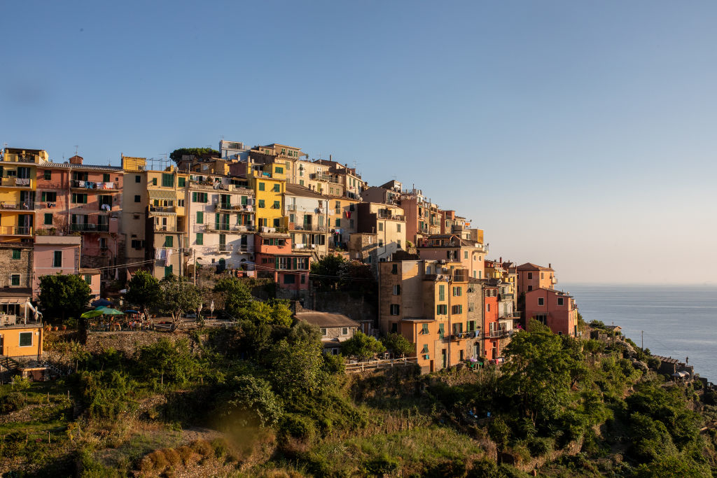 A scenic view of a coastal hillside village with many colorful, closely-packed buildings against a backdrop of the sea and a clear sky.