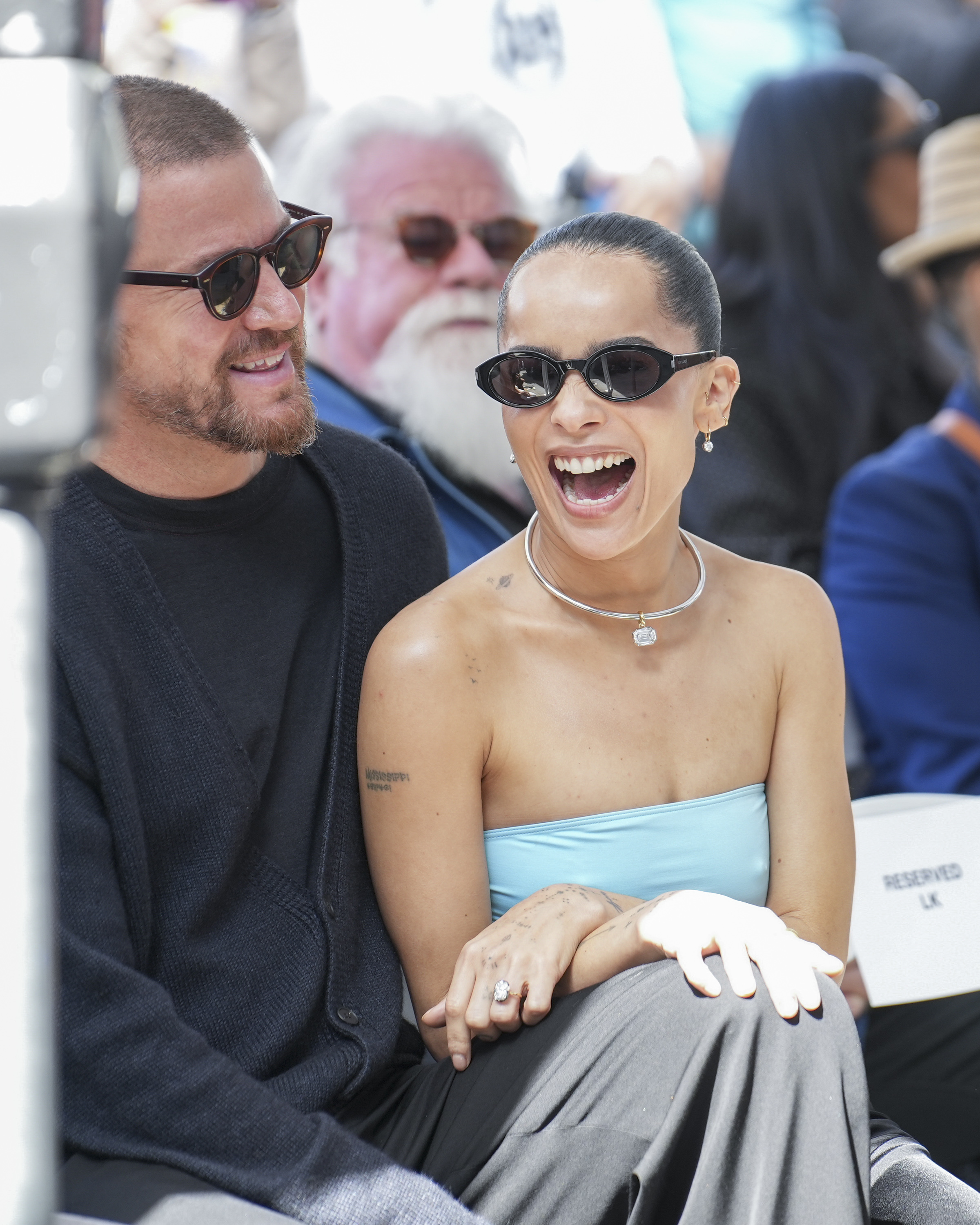 Zoe Kravitz, in a strapless outfit and sunglasses, laughing with Channing Tatum, also in sunglasses, at an outdoor event