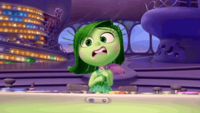 Disgust from &quot;Inside Out&quot; stands at a console, holding a microphone with an expression suggesting distaste or concern