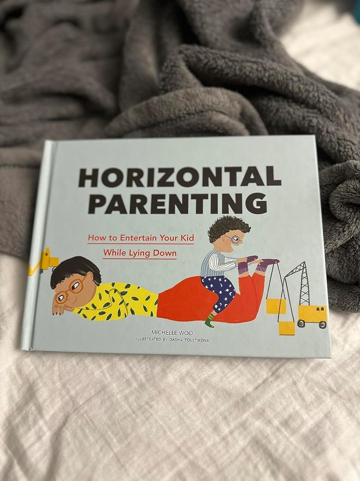 Cover of the book &quot;Horizontal Parenting&quot; by Michelle Woo, illustrated by Dasha Tolstikova, with parents lying down entertaining kids