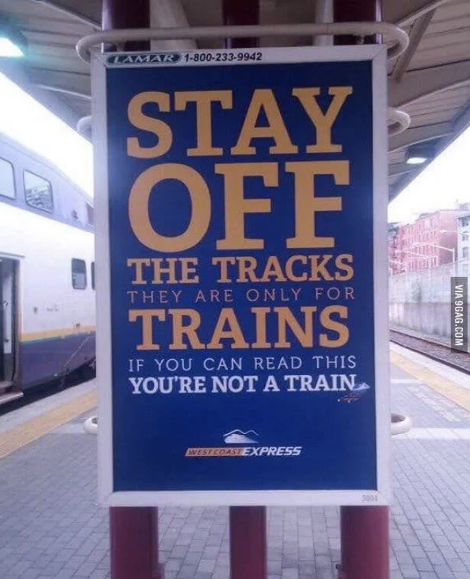 Train safety sign reads: "STAY OFF THE TRACKS. THEY ARE ONLY FOR TRAINS. IF YOU CAN READ THIS YOU'RE NOT A TRAIN." Advertising the West Coast Express