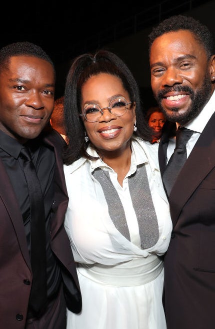David Oyelowo, Oprah Winfrey, and Colman Domingo smile while posing together at an event, dressed in formal attire