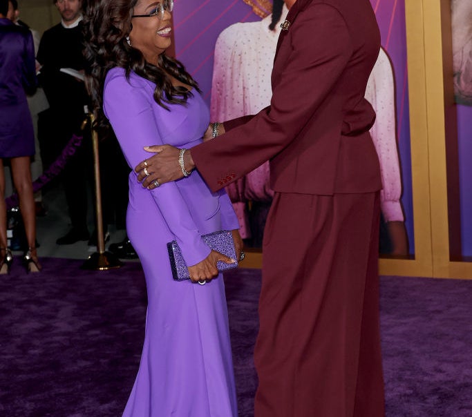 Oprah Winfrey and Corey Hawkins in formal attire, smiling and greeting each other at a formal event