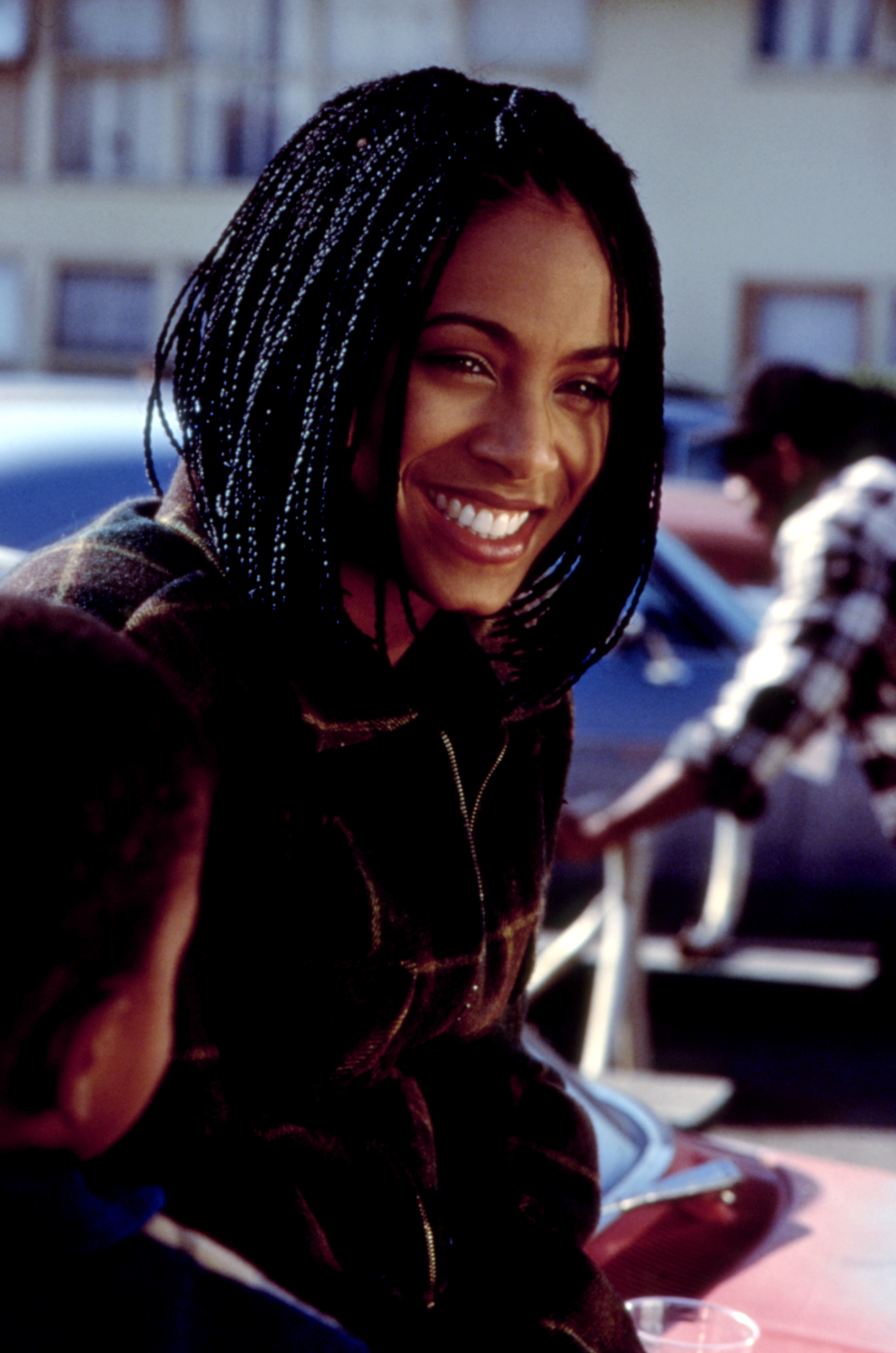Jada Pinkett Smith smiles while wearing a casual plaid jacket
