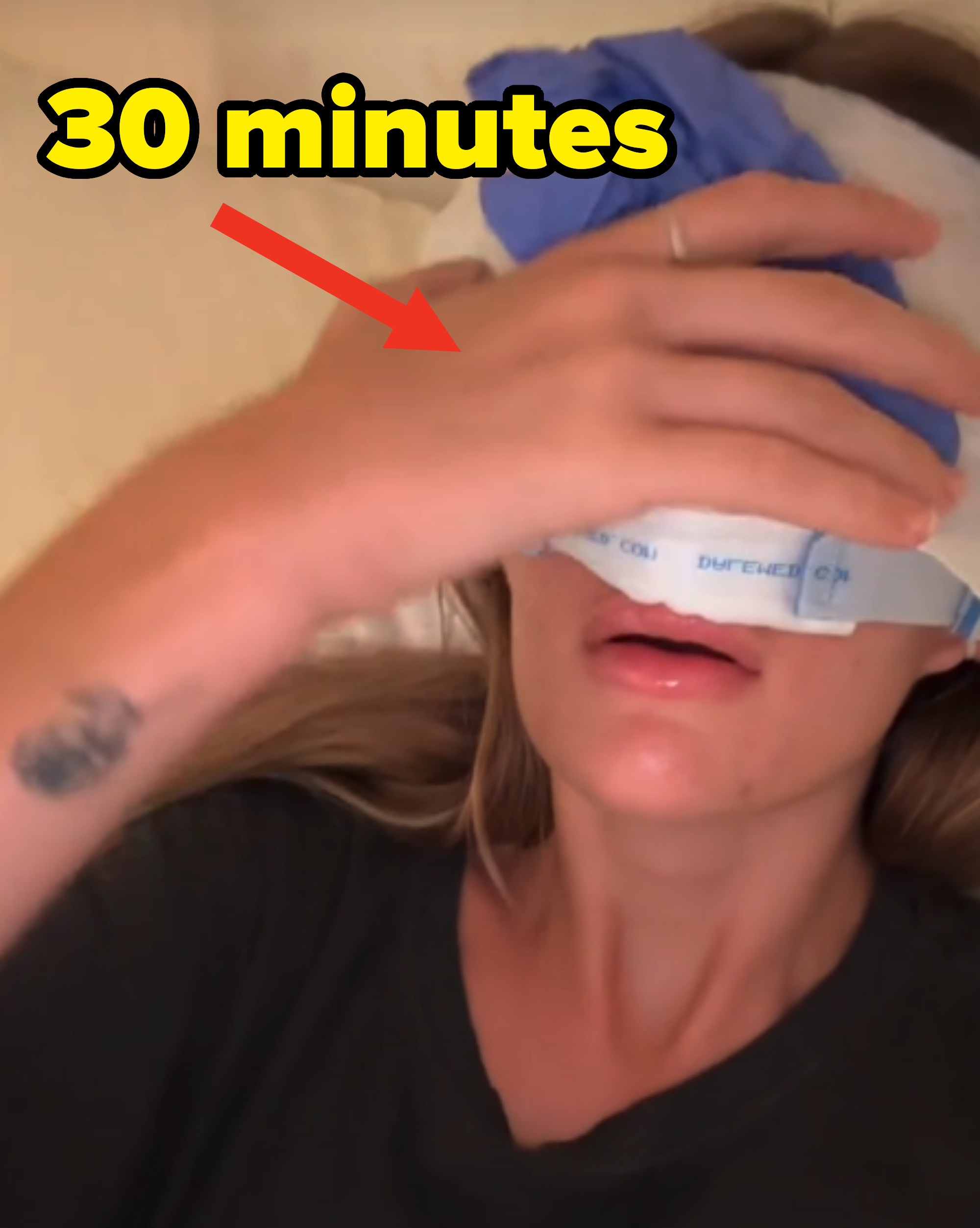Sami lying in bed with an ice pack on her eyes and a hand resting on her forehead. She's wearing a dark t-shirt