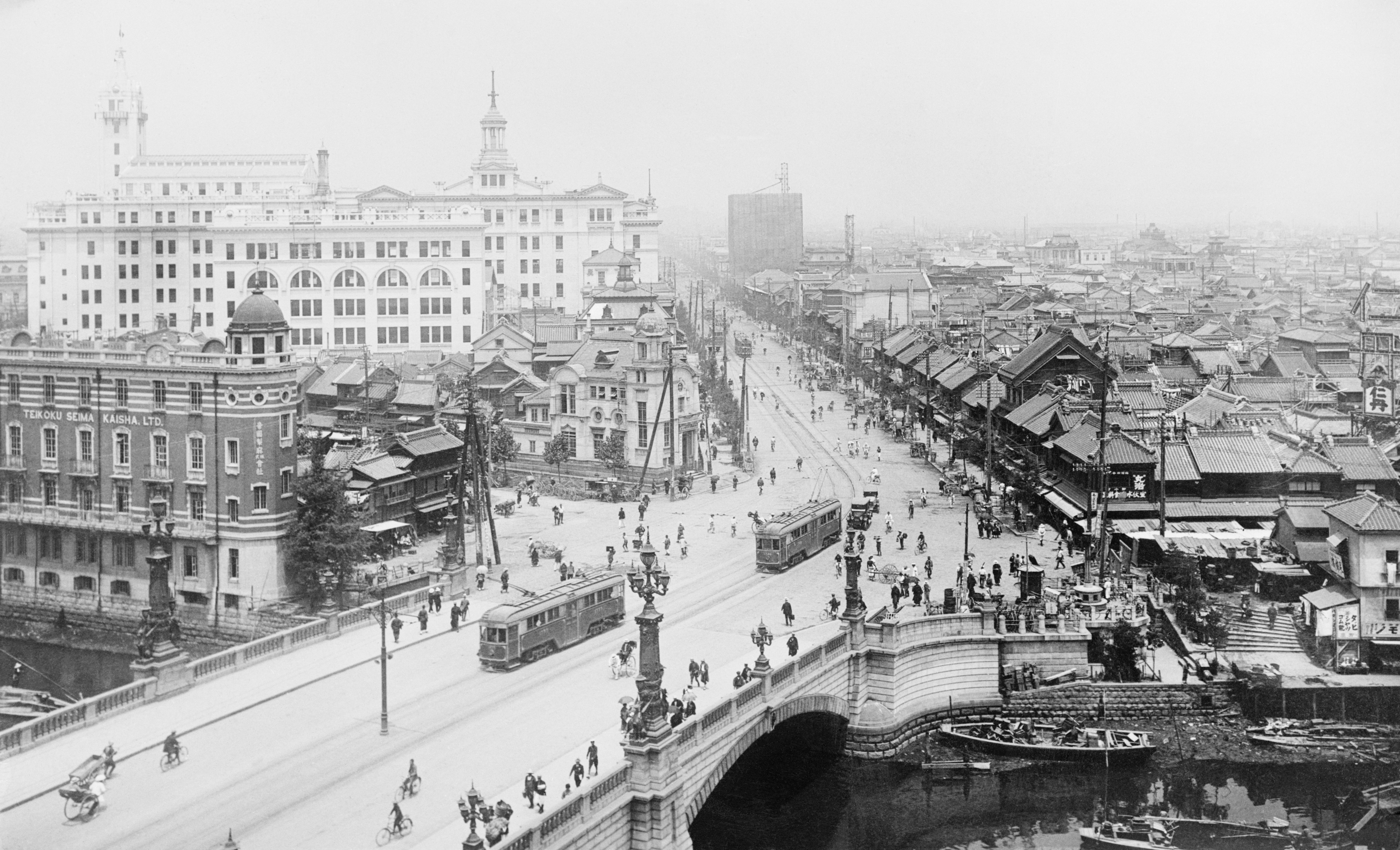 Historic cityscape view with a busy bridge, trams, cyclists, and pedestrians; surrounded by many traditional buildings and a few larger structures