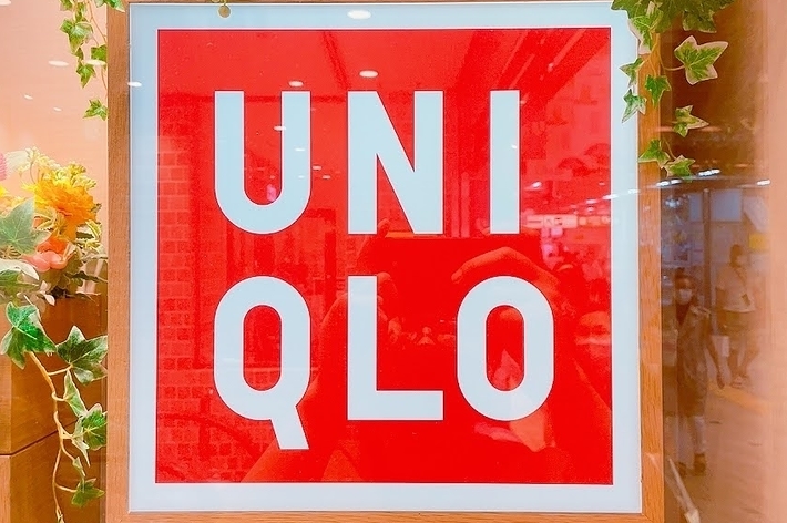 Uniqlo store sign with a red background and white text, framed by decorative plants
