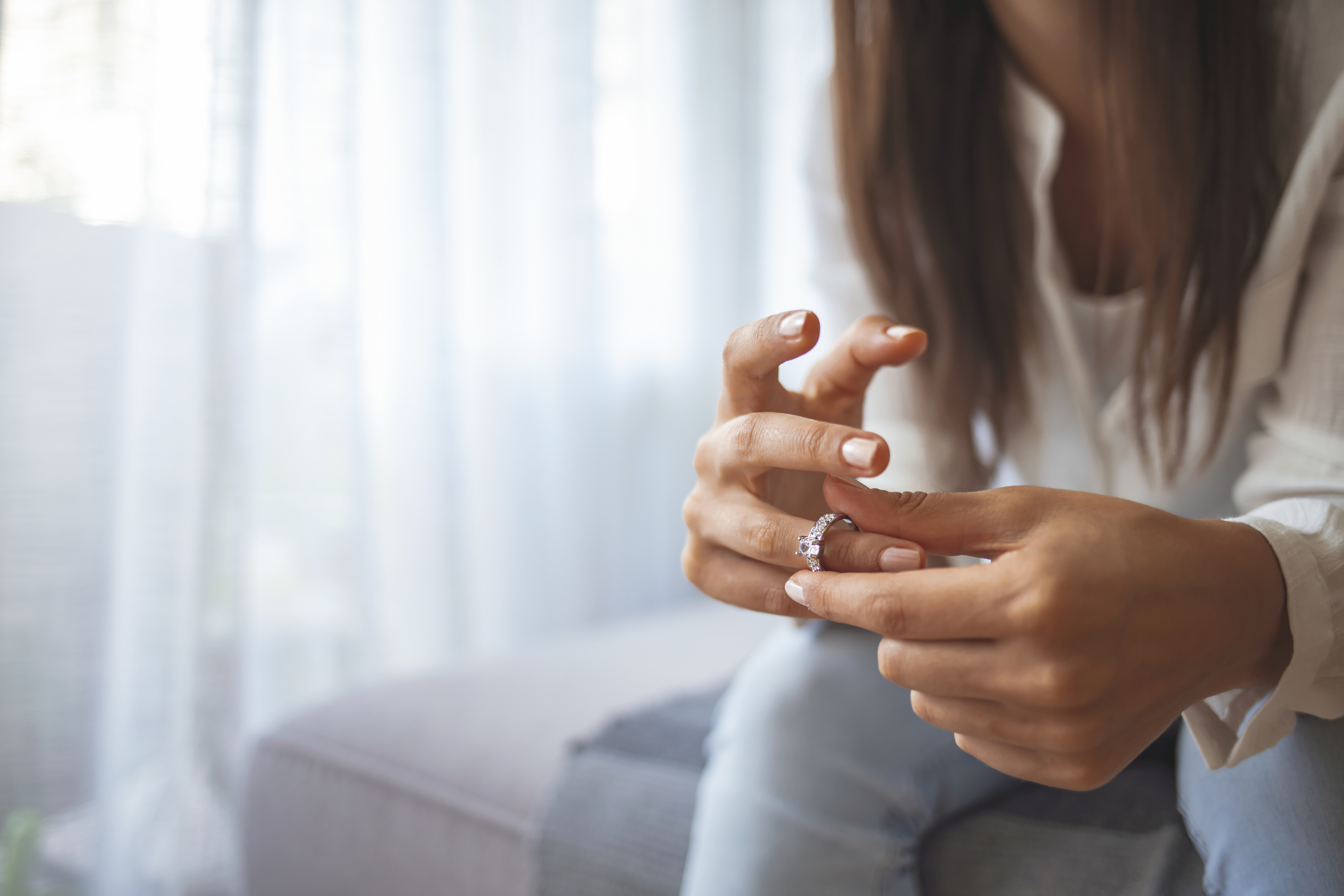 Close-up of a woman seated on a couch, removing a ring from her finger