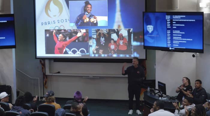 Multiple screens display images of Simone Biles and Paris 2024 Olympics branding