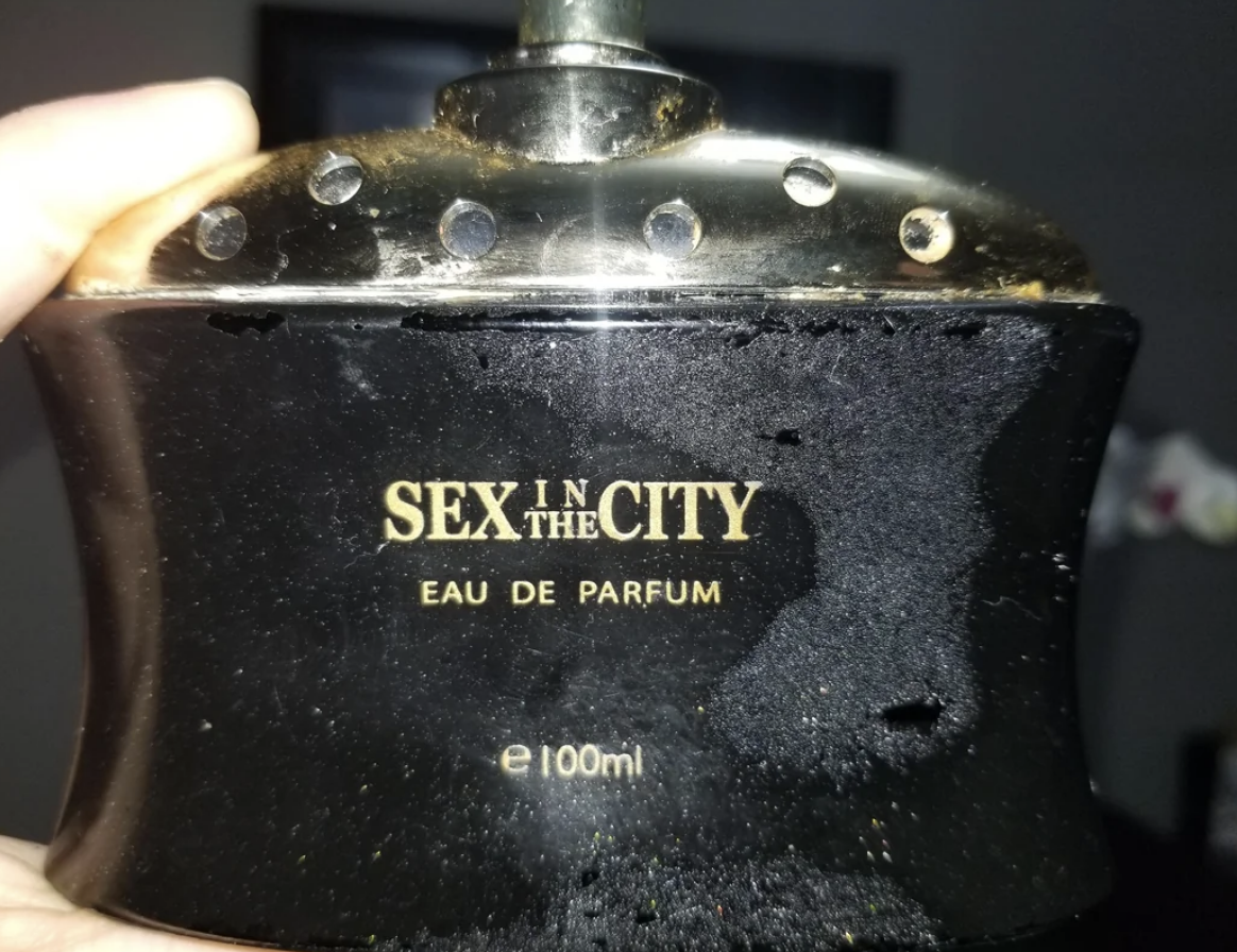 A hand holding a "Sex in the City" Eau de Parfum bottle, 100ml size