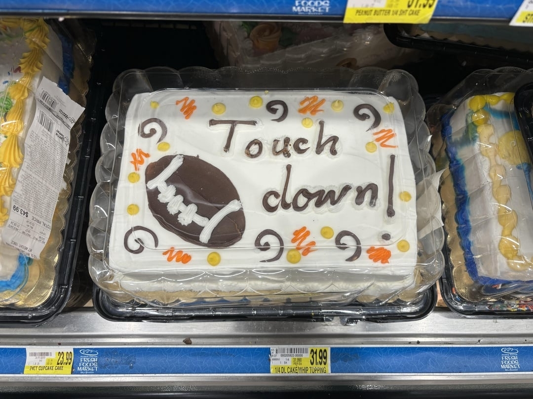 Touchdown cake with a football design and the typo "Touch clown" on it, displayed in a grocery store